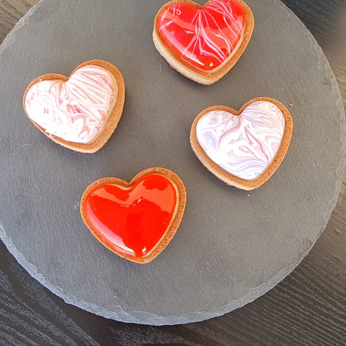 Tartellette a forma di cuore con gelatina di frutta su pietra scura